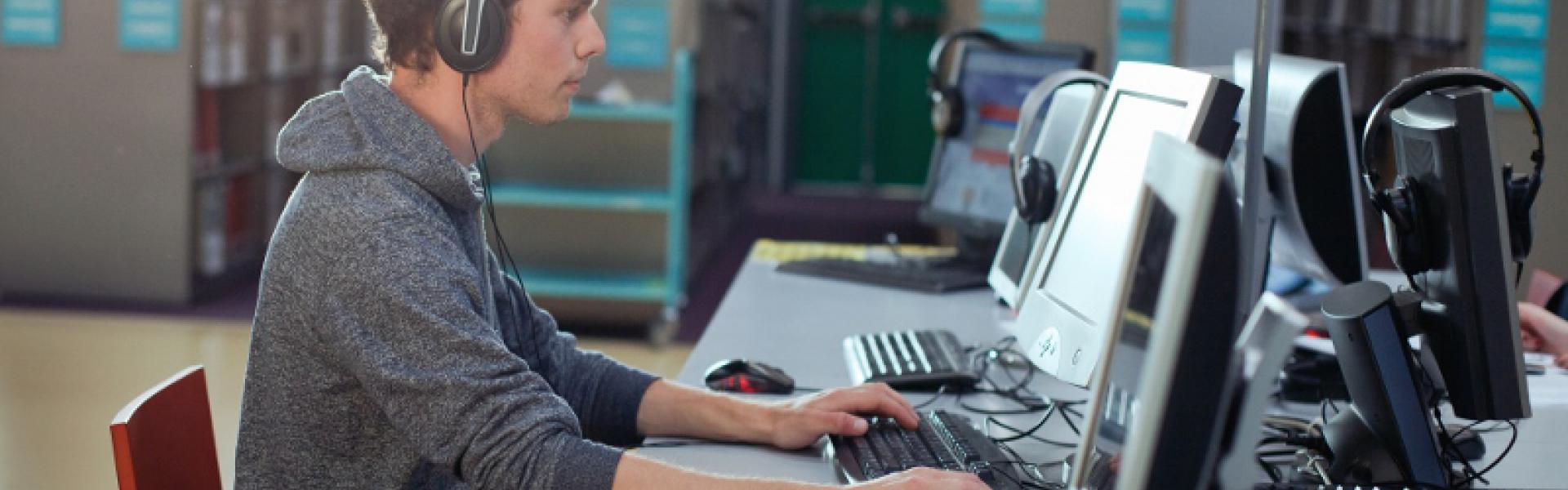 Man wearing a headset and focusing on a computer-based training.