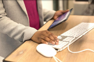  Person looking at tablet while typing on keyboard. Licence: Creative Commons Attribution UKBlackTech