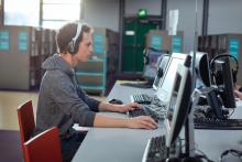 Man wearing a headset and focusing on a computer-based training.