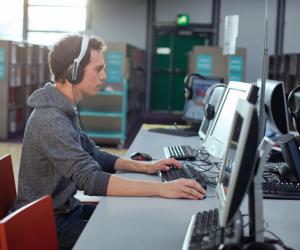 Man wearing a headset and focusing on a computer-based training.