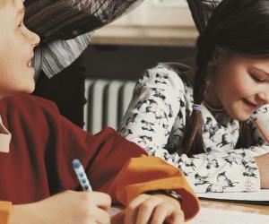 A girl and a boy studying with their teacher helping.