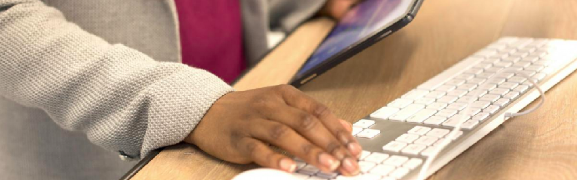  Person looking at tablet while typing on keyboard. Licence: Creative Commons Attribution UKBlackTech